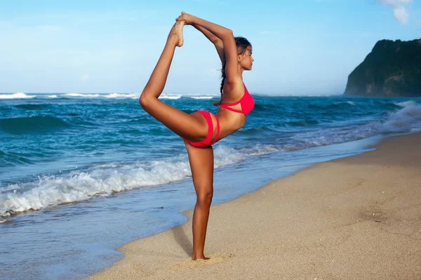 Jeune femme pratiquant le yoga sur la plage au lever du soleil — Photo