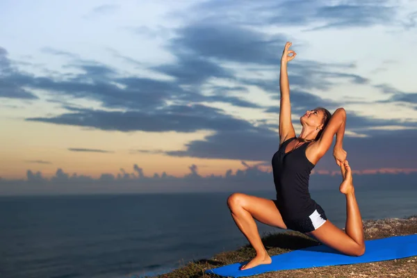 Frau praktiziert Yoga auf einem Felsen über dem Meer. — Stockfoto