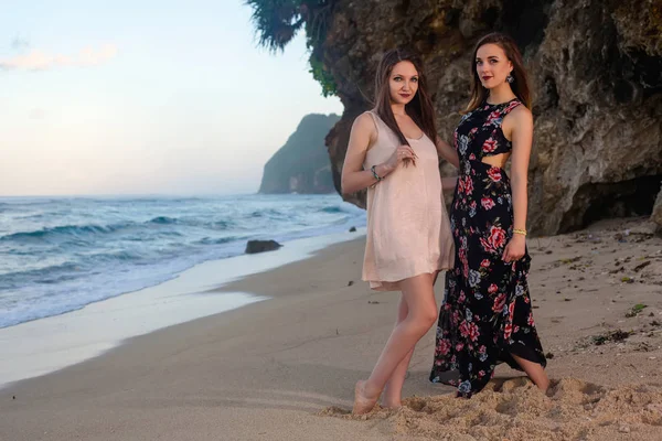 Deux filles posant sur la plage devant le rocher . Image En Vente