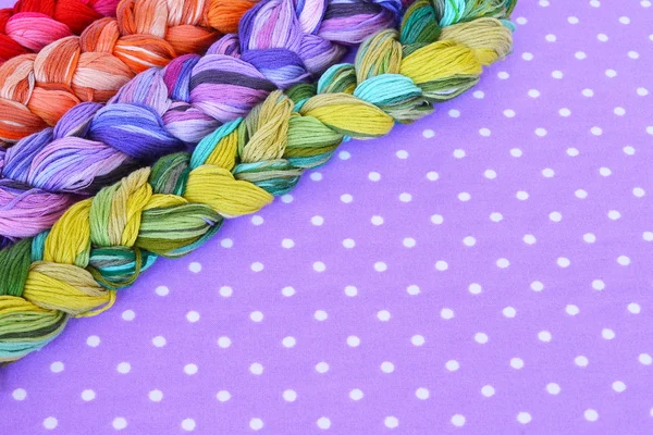 Hilos de bordado de diferentes colores sobre fondo púrpura — Foto de Stock
