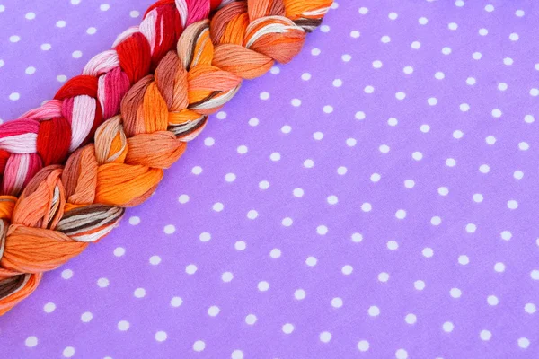 Trådar för broderi i olika färger på en lila bakgrund — Stockfoto