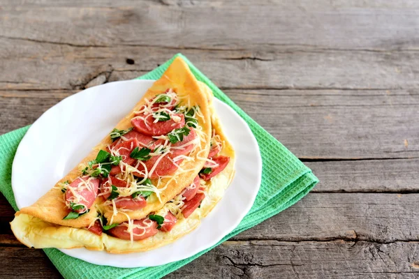 Herzhaft gefülltes Omelett auf einem Teller. Omelett gefüllt mit Wurst, Käse und Petersilie auf einem alten hölzernen Hintergrund mit leerem Platz für Text. nahrhaftes Frühstück Rezept — Stockfoto