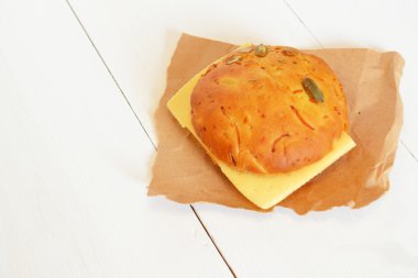 Bir dilim peynir kağıt ve beyaz tahta arka plan ile bir sandviç 