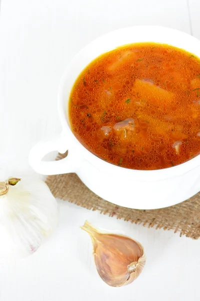 Sup kubis di piring dengan latar belakang kayu putih. Bawang putih. Sayuran sup kubis putih, kentang, tomat, bawang putih, herbal — Stok Foto