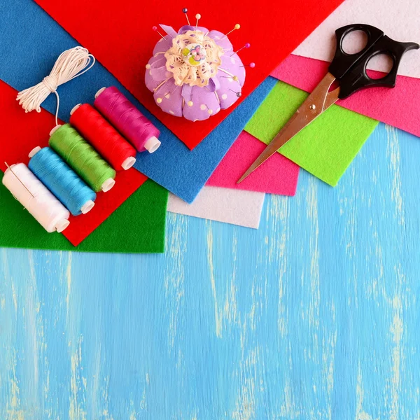 Colored felt sheets, sewing kit, scissors, pins, pincushion, white ribbon on blue wooden background with empty space for text. Sewing supplies. Needlework concept — Stockfoto