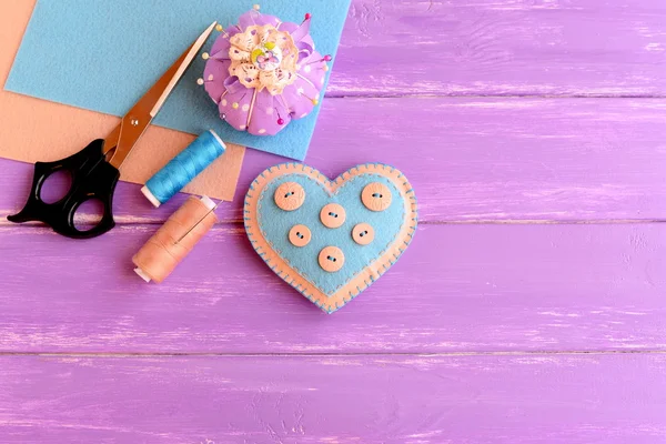 How to make a felt heart crafts. Step. Decorative felt heart, scissors, thread, needle, felt sheets, pincushion, pins on wooden background. Crafts project for Valentine's day, wedding, mother's day — Stock Photo, Image