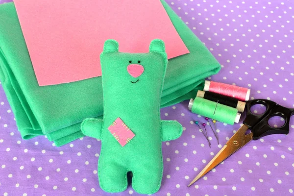 Милый зеленый войлочный мишка Тедди, детский игрушечный фон. Ножницы, цветные нити боббинс, иглы - швейный набор, аксессуары для портных. Мягкое фото игрушечного медведя. Счастливый вид плюшевого медведя Стоковое Изображение