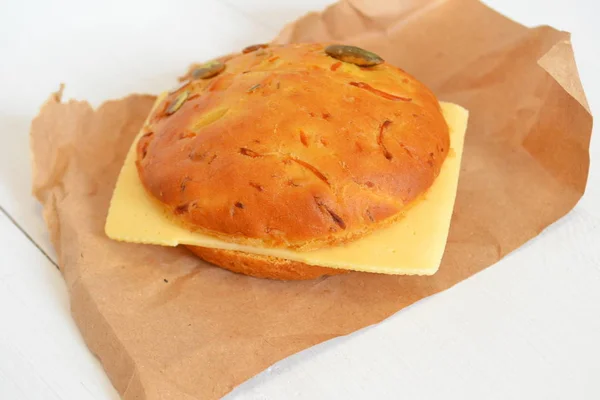 Сэндвич с кусочком сыра на бумаге и белым деревянным фоном — стоковое фото
