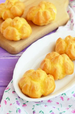 Dolgu ile lezzetli tatlı eklerleri. Ev yapımı tereyağı bir plaka ve ahşap kesme tahtası üzerinde krema dolu eklerleri. Portre 