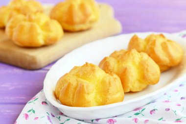 Dolgu ile lezzetli tatlı eklerleri. Ev yapımı eklerleri tereyağı krema bir plaka ve ahşap kesme tahtası ile dolu. Portre 