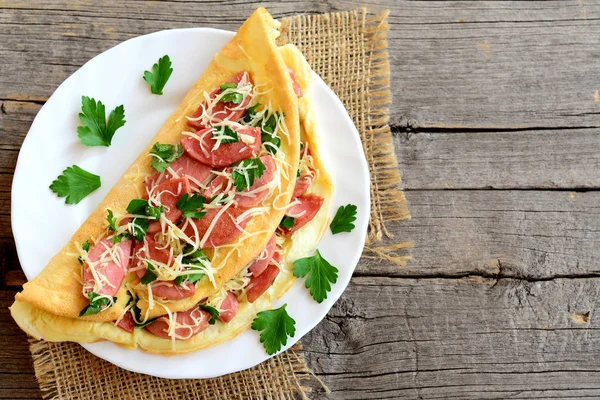 Leckere Wurst-Käse-Omelette auf einem Teller und einem alten Holzhintergrund mit leerem Kopierraum für Text. Eier-Omelett mit Füllung. Vintage-Stil. Ansicht von oben — Stockfoto