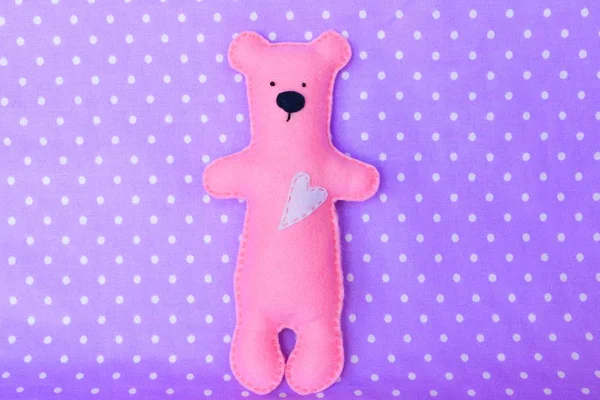 Urso de feltro - urso de feltro rosa artesanal no fundo de lavanda, brinquedo costurado à mão — Fotografia de Stock