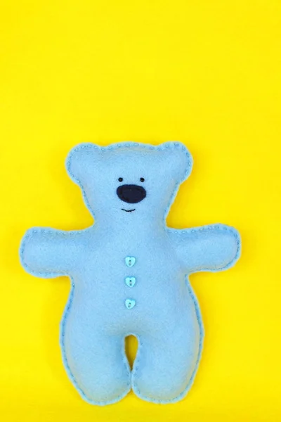 Oso de fieltro - oso de fieltro azul sobre fondo amarillo, juguete cosido a mano, una artesanía de fieltro —  Fotos de Stock