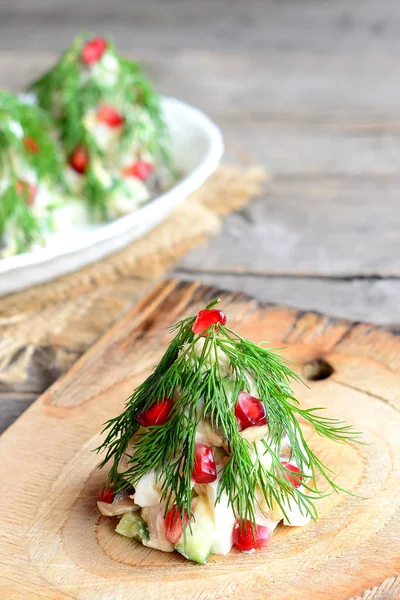 Christmas tree salad on a wooden board. Delicious festive salad with meat, champignons, cucumbers and eggs decorated with dill and pomegranate. Christmas food. Old wooden table. Christmas dinner meal table. Vintage style. Closeup — Stock Photo, Image