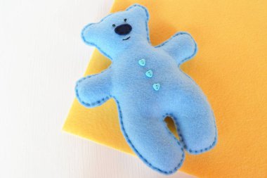 Sarı arka plan, Elle dikilmiş oyuncak, keçe dışında bir craft el yapımı keçe ayı - mavi keçe ayı