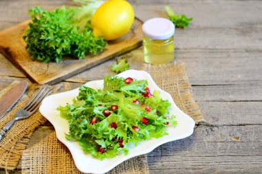 Sağlıklı marul Nar ile limon suyu ve zeytinyağı ile giyinmiş. Parlak kolay vejetaryen salata. Bir tabak, malzemeler, çatal, metin için kopya yer ile ahşap arka plan üzerinde bıçak üzerinde hafif salata 