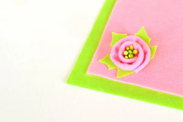 Pink flower with green leaf on a color felt and white wooden background — Stock Photo, Image