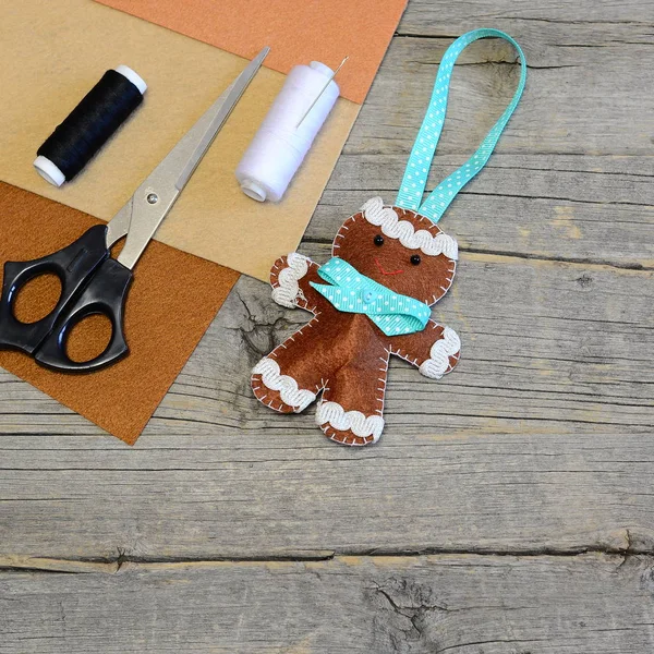 Christmas tree gingerbread man decor. Homemade hanging decor, scissors, thread, needle, brown felt pieces on old wooden table with copy space for text. Quick and easy Christmas sewing diy for kids — Stock Photo, Image