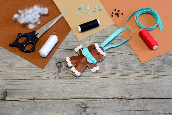 Christmas tree gingerbread man decor, scissors, thread, needle, filler, felt sheets, beads, buttons on old wooden table. Cute Christmas felt crafts for children. Easy handcraft idea. Vintage style — Stock Image Christmas tree gingerbread man decor, scissors, thread, needle, filler, felt sheets, beads, buttons on old wooden table. Cute Christmas felt crafts for children. Easy handcraft idea. Vintage style Stock Photo