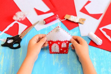 Çocuk bir keçe yılbaşı ağacı ev süs yapılmış. Çocuk tutan Noel ev süsleme onun elinde. Araç ve Gereçleri dikiş zanaat projeleri için. Çocuklar için kış el sanatları. Mavi ahşap arka plan 