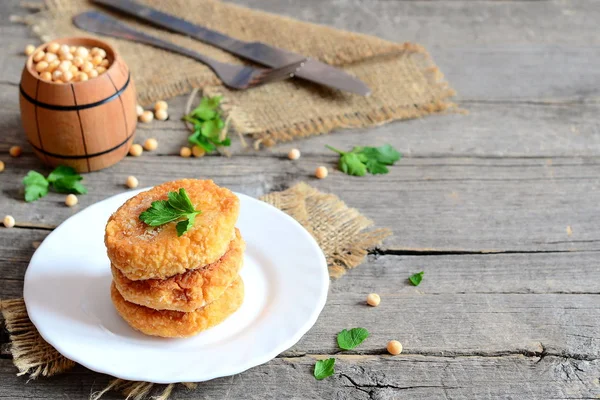 Tăieturi de mazăre prăjite pe farfurie. Tăieturi vegane sănătoase gătite din mazăre galbenă uscată și decorate cu pătrunjel. Furculiță, cuțit pe un fundal vechi din lemn cu spațiu de copiere pentru text. Idee de mâncare vegană. Closeup — Fotografie, imagine de stoc