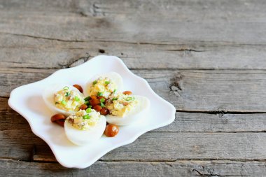 Klasik kopya alanı metin için eski ahşap zemin üzerine izole bir tabakta yumurta dolması. Haşlanmış yumurta, peynir, mantar ve yeşil soğan ile doldurulmuş. Lezzetli vejetaryen yemek tarifi 
