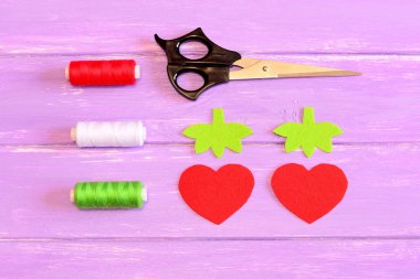 How to hand sew a children toy strawberry. Step. Tutorial. Parts cut from red and green felt in the shape of strawberries and leaves. Scissors, thread on a wooden table. Fun sewing lesson. Top view  clipart