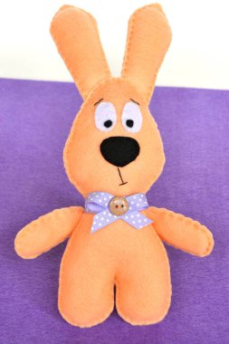 El yapımı keçe bej tavşan bir mor keçe ve beyaz arka plan üzerinde