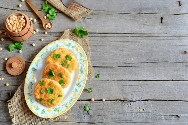 上一盘油炸豌豆肉饼。健康的饮食肉饼从黄色干豌豆煮熟，用欧芹装饰。与旧木背景与副本空间上干豌豆的小桶。素食的食物 — 图库照片