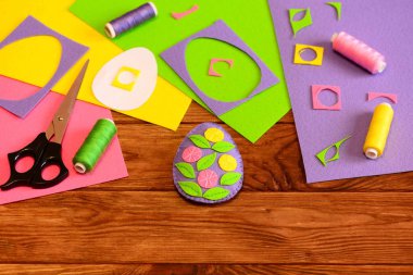 Çiçekler, makas, Tel, iğne, kağıt şablonu, bir güzel keçe Paskalya yortusu yumurta dekor renkli keçe çarşafları ve hurda ahşap bir masa üzerinde. Ev yapımı Paskalya dekor fikir çocuklar için