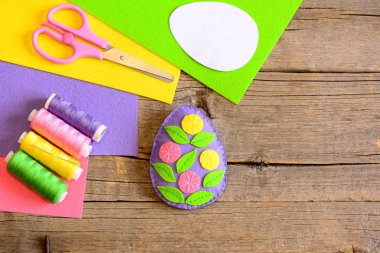 Paskalya yortusu yumurta dekor çiçek ve yaprakları ile hissettim. Basit Paskalya resim sanatı. Öğretim dikiş becerileri çocuklar. Makas, iş parçacığı grubu, yaprak, ahşap arka plan kopya alanı ile kağıt şablonu hissettim. Üstten Görünüm
