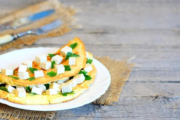 Tortilla de tofu vegetariana baja en grasa en un plato blanco. Tortilla frita rellena de tofu y perejil fresco. Tenedor y cuchillo sobre fondo de madera con espacio vacío para texto. Receta de huevo vegetariano — Foto de Stock