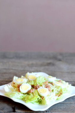 Bir tabak ve vintage ahşap masa üzerinde ev yapımı lahana salatası ton balığı ve Bıldırcın yumurta. Salata taze napa lahana, konserve ton balığı ve haşlanmış bıldırcın yumurtası ile yapılmış. Dikey fotoğraf