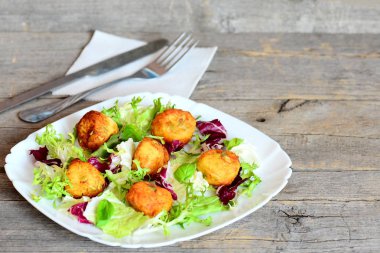 Çıtır çıtır kızarmış patates topları. Lezzetli kızarmış patates püresi kabak çekirdeği taze marul ve bir plaka üzerinde fesleğen ile süslenmiş toplarla. Çatal bıçak takımı, metin için boş yer vintage ahşap zemin üzerine peçete 