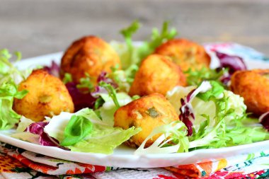 Çıtır çıtır kızarmış patates püresi topları. Lezzetli kızarmış topları patates püresi kabak çekirdeği ile yapılmış salata yaprakları karışımı ve fesleğen bir tabakta servis. Portre