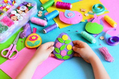 Çocuk bir keçe Paskalya yortusu yumurta süs yapılmış. Küçük çocuk bir keçe Paskalya yortusu yumurta süsleme elinde tutar. Paskalya el sanatları, el sanatları araçları ve malzemeleri bir tablo. Festival bahar el sanatları kavramı 