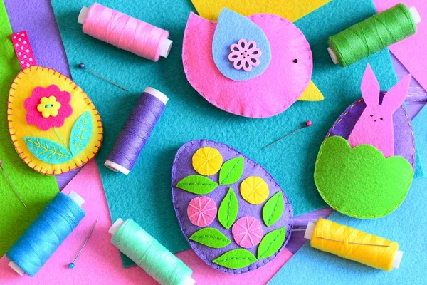 Felt Easter eggs with flowers and bunny, a bird. Easter DIY set, colored thread spools, felt sheets, pins on a table. Colorful Easter craft background for children and beginners. Top view. Closeup — Stock Photo, Image