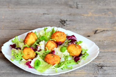 Altın kızarmış patates püresi kabak çekirdeği ile Beşamel sos taze marul mix ve bir plaka üzerinde fesleğen ile devam eder. Ahşap arka plan kopya alanı metin için ile. Hızlı ve lezzetli patates pirzola tarifi