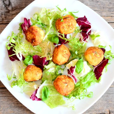 Kızarmış patates topları taze marul ve fesleğen bir plaka üzerinde ve ahşap arka plan üzerinde kabak çekirdeği ile püre. Kolay ve lezzetli patates topları tarifi. Üstten Görünüm