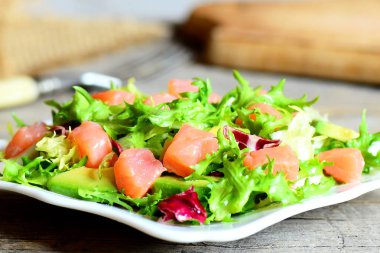 Lezzetli ve basit somon salata bir plaka üzerinde. Somon füme, salata karışımı ve taze avokado ve soyunma zeytinyağı ve limon suyu ile hazırlanan salata. Vintage tarzı. Portre