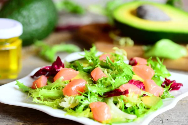 Лосось, авокадо и салат из салата. Домашний салат с ломтиками лосося, свежим авокадо и листьями салата на тарелке. Авокадо, оливковое масло на деревянном столе. Крупный план — стоковое фото