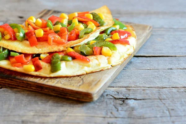 Tortilla de verduras rellenas sobre tabla de madera. Tortilla frita rellena de pimientos rojos y verdes y maíz enlatado. Receta de huevos de desayuno. Estilo rústico. Primer plano. — Foto de Stock