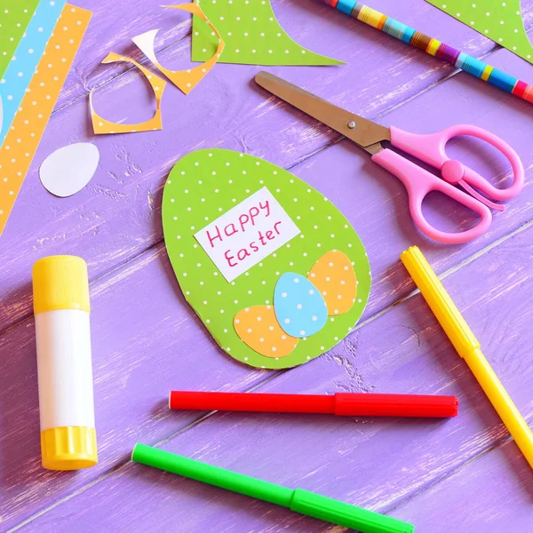 Happy Easter card in egg shape. Materials and tools to create Easter paper greeting card. Easy and fun Easter paper crafts for kids