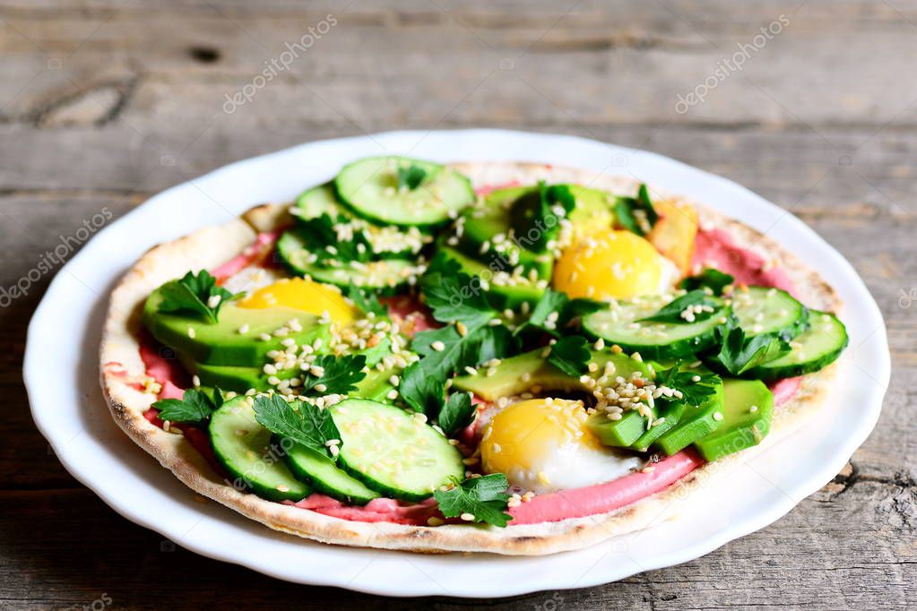 Homemade tacos with fried quail eggs, avocado, cucumber, beet hummus and parsley. Quick and easy breakfast tacos on a plate isolated on vintage wooden table. Healthy meal idea