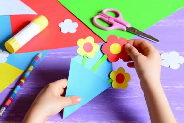 Küçük çocuk anne gün veya doğum günü için kağıt el sanatları yapar. Küçük çocuk anne için kağıt çiçek yapmak. Basit ve güzel bir hediye fikri. Makas, yapıştırıcı, çiçek şablonları, ahşap bir masa üzerinde kalem