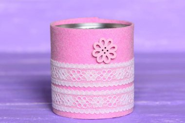 Recycled can isolated on wood background. Tin can decorated with felt, lace and flower button. Inexpensive way to make craft projects for home. Recycling tin can into organizer or planter for kitchen  clipart