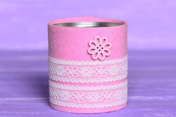 Recycled can isolated on wood background. Tin can decorated with felt, lace and flower button. Inexpensive way to make craft projects for home. Recycling tin can into organizer or planter for kitchen 