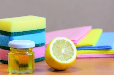 Mutfak süngeri temizleme seti, cam kavanozda zeytin yağı, ahşap masada limon yarısı. Eko ev temizlik malzemeleri hazır. Zehirli olmayan organik mutfak temizleme ürünleri. Yakın çekim.