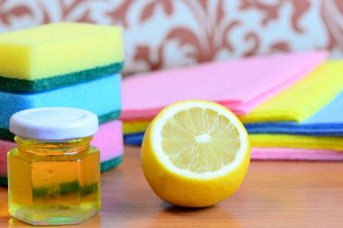 Yıkama süngeri, fırça takımı, kavanozda zeytin yağı, ahşap bir masada limon yarısı. Eko ev temizliği fikri. Limonlu doğal ev temizleme ürünü. Eko güvenli ürünler. Yakın çekim.