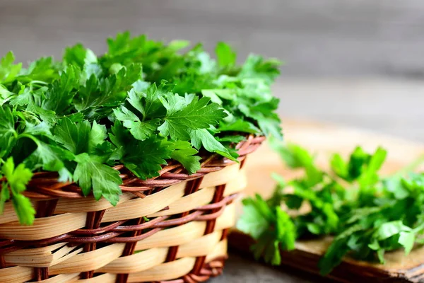 Fresh green parsley sprigs in a wicker basket and wooden board. Garden parsley plant. High source of flavonoid and antioxidants, folic acid, vitamin K, vitamin C and vitamin A. Rustic style. Closeup — Stock Photo, Image